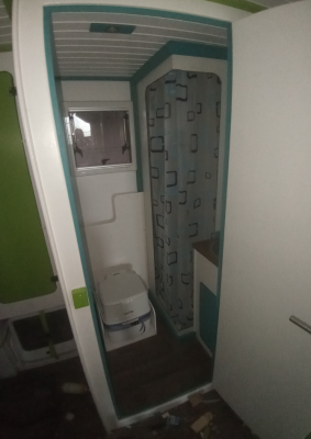 Ein Blick durch die Tür ins innere. Hinter dem Wandvorsprung hinter dem Porta-Potti verlaufen alle Wasserleitungen und die Anschlüsse für die Brausearmatur.