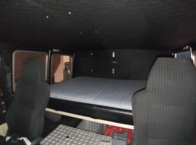 Die alte Rückenlehne der Sitzbank polstert jetzt die vordere Kante des Bettes. Auf dem Foto fehlt noch die Abdeckung damit man nicht unter das Bett schauen kann.