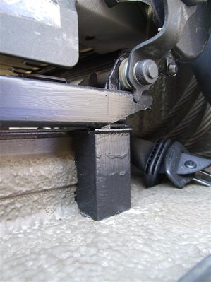 Fahrersitzbefestigung hinten links.<br />Hier habe ich wieder eine Bohrung in den Kabinenboden gemacht - ganz dicht neben der Konsole - und mit einem Stück Gewindestab den Sitz verankert. Zur Stabilisierung hab ich ein kurzes Stück von dem Hutprofil, das ich vorne quer auf der Konsole montiert habe, hochkant eingebaut und genau an das seitliche Profil der Konsole angepasst. Es fungiert so als Stütze für die Druckkräfte, den Zug nimmt die Gewindestange auf.